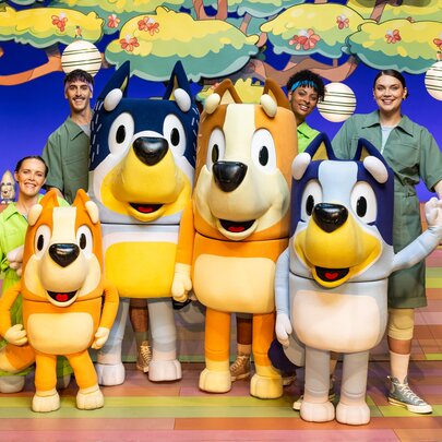 Bluey stage show human and puppet cast with tree background.