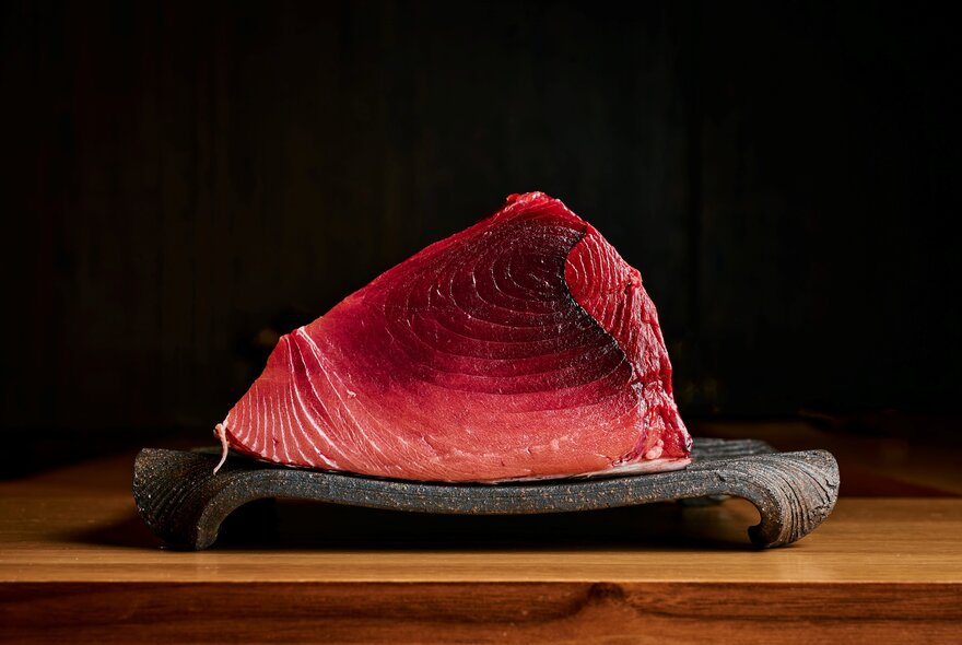 Slab of red tuna meat on a slab of stone.