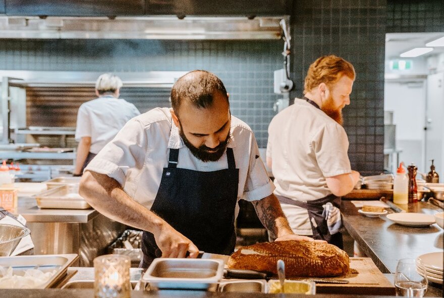 Chefs in a restaurant's commercial kitchen preparing food.