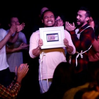 Person holding a certificate, being applauded by onlookers.
