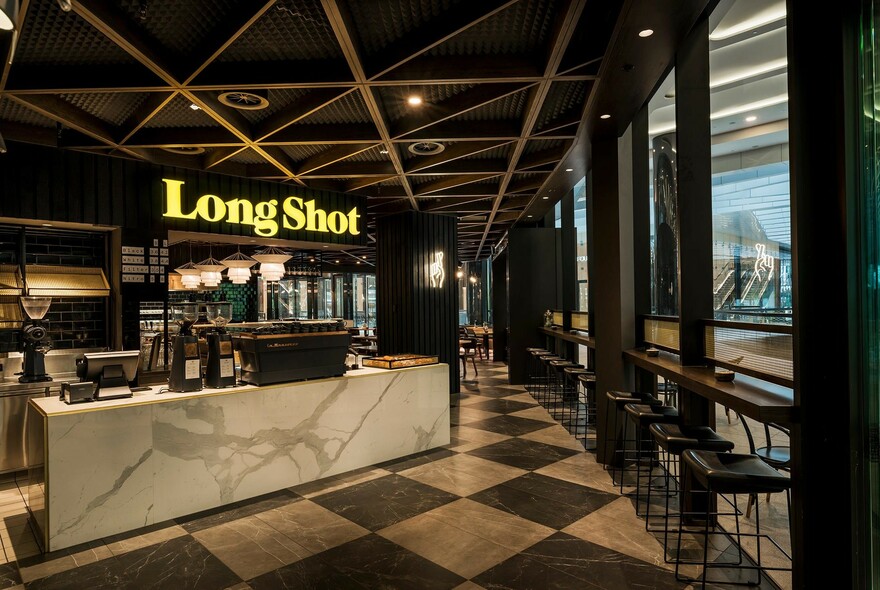 Cafe interior with signage, marble counter with coffee machine, diamond-patterned floor.