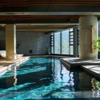 Hotel indoor pool with blue water and daybeds.