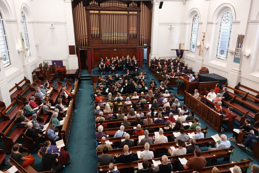 The interior of Collins Street Baptist Church with people seated and a grand organ. 