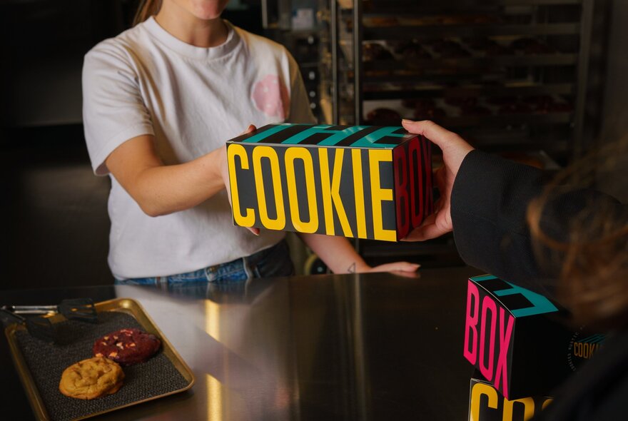 Server handing a branded box of cookies to a customer.