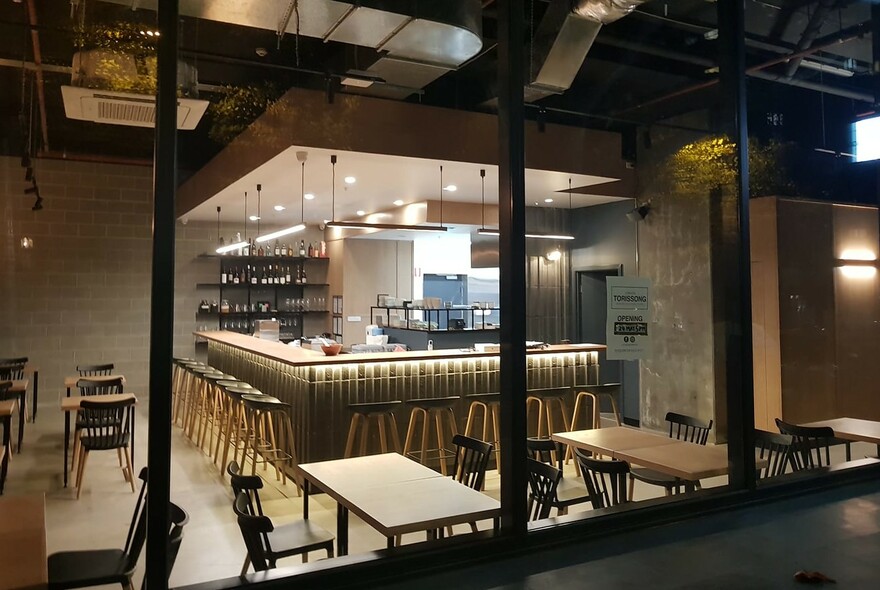 Chairs and tables surrounding kitchen area and counter with stools.