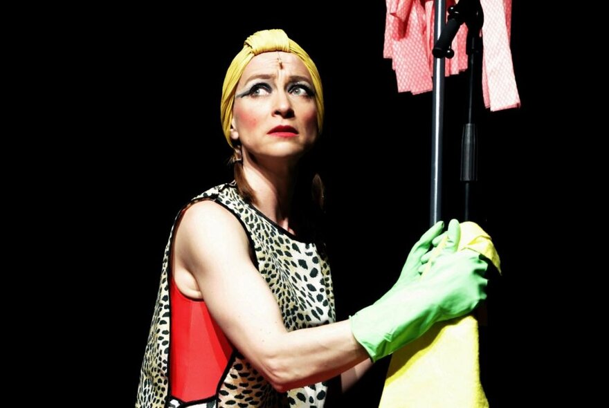 UK performer, Sarah-Louise Young, performing in character as Kate Bush on a darkened theatre stage.