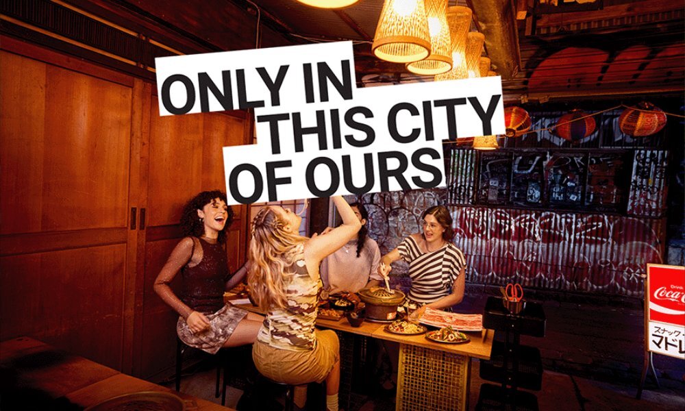 Four friends enjoying a Korean barbecue dinner in a dimly lit restaurant. Text overlay reads 'only in this city of ours'.