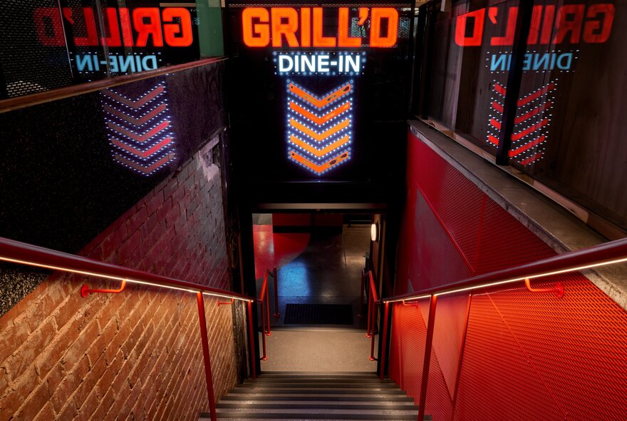 Stairs leading down into a restaurant entrance with red and orange neon 'Grill'd Dine-In' signs.