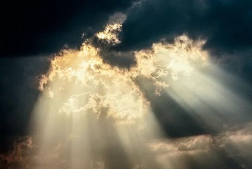 Beams of sunlight escaping through dark clouds.