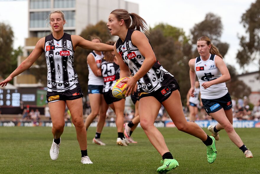 Collingwood and Carlton AFLW players during a match. 
