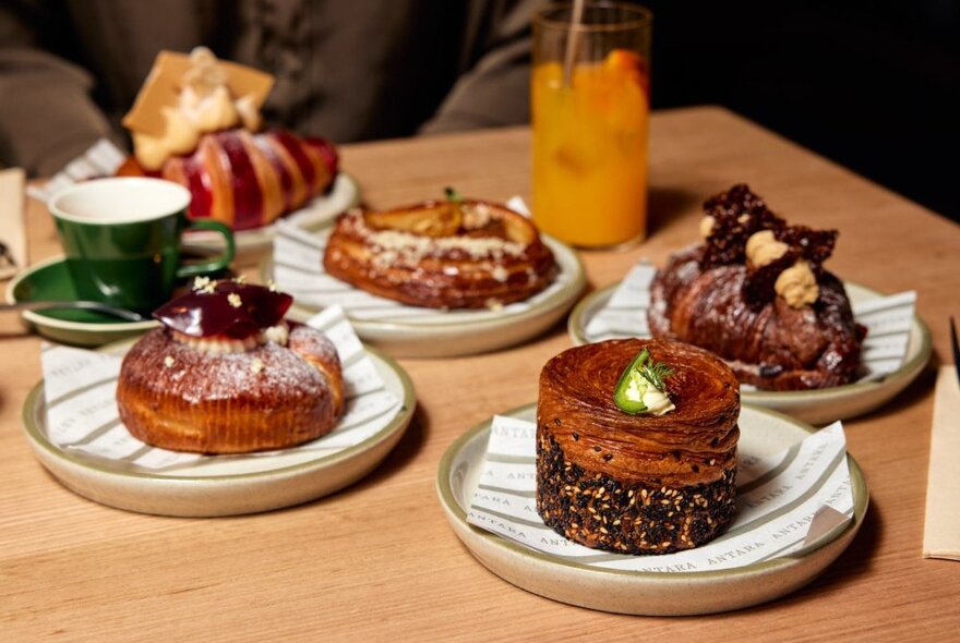 Wooden table with pastries, coffee and juice.