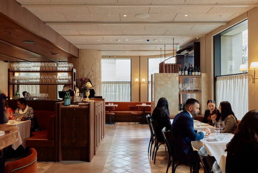 The interior of Harriott restaurant with soft lighting, tables arranged near the curtained windows, and a wooden floor.