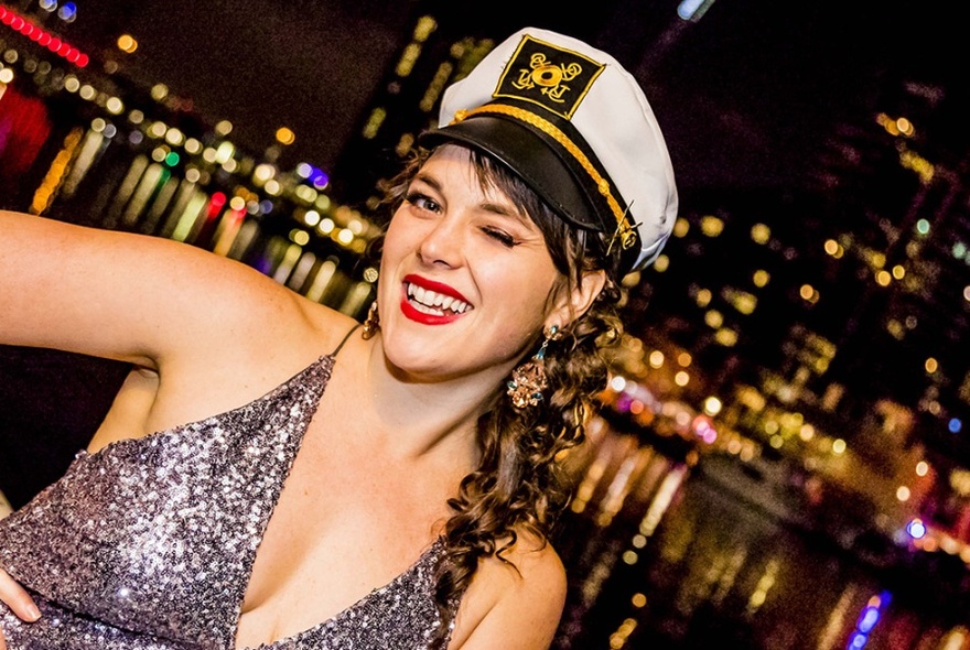 Woman in sequinned dress and sailor's cap, winking.