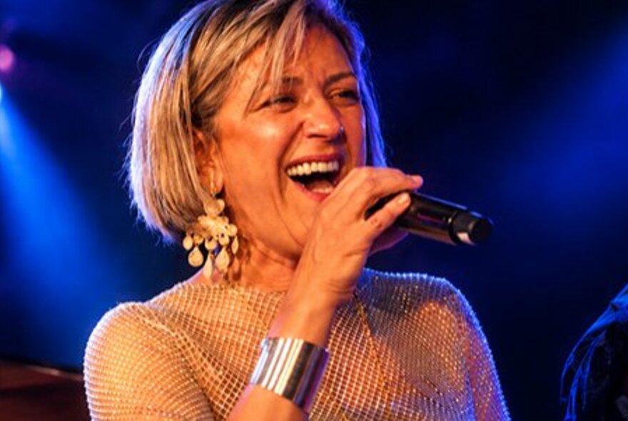 Singer Noria Letts performing live on stage, singing into a microphone.
