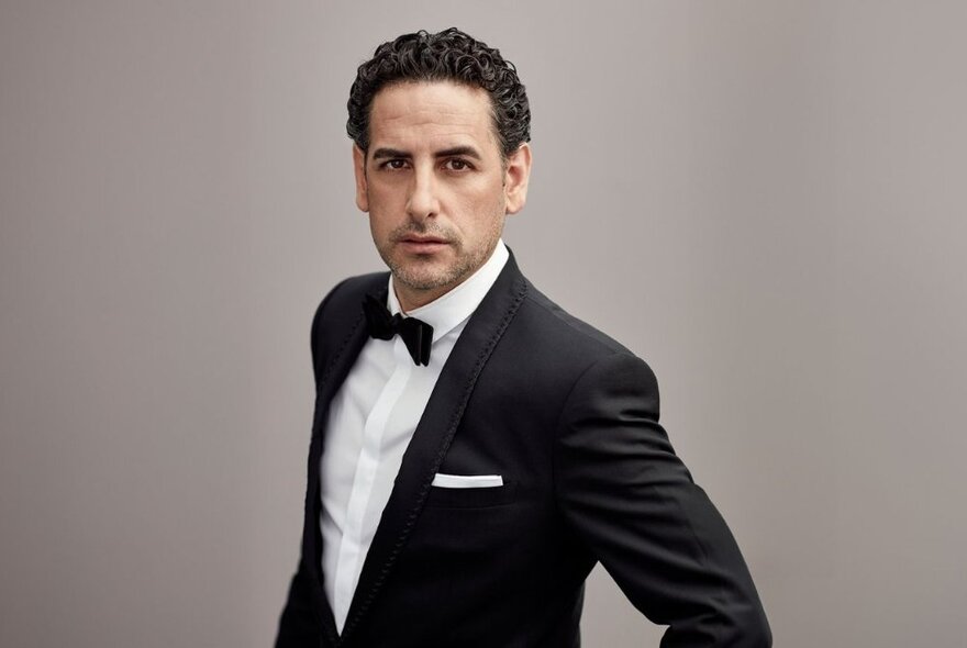 Peruvian tenor Juan Diego Flórez, standing side on, wearing a tux and bow tie.