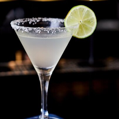 A margarita in a cocktail glass, with a salted rim and a slice of lime as garnish.