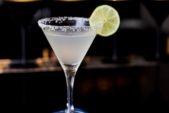 A margarita in a cocktail glass, with a salted rim and a slice of lime as garnish.