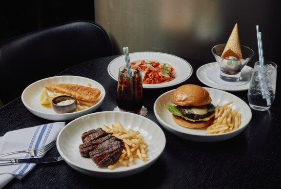 Kids meals of burgers and fries with party hats and drinks.
