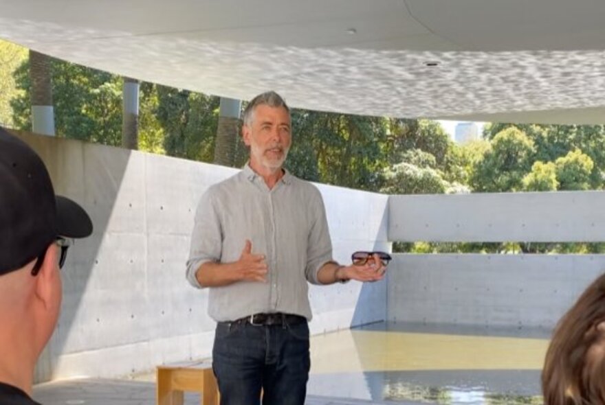 A tour guide with presenting in front of a small group at MPavilion. 