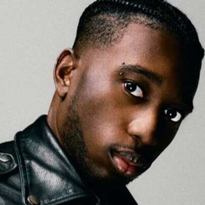 Musician wearing a black leather jacket with cropped hair.