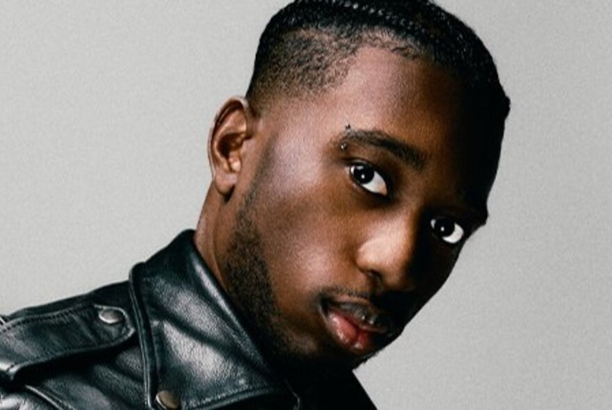 Musician wearing a black leather jacket with cropped hair.