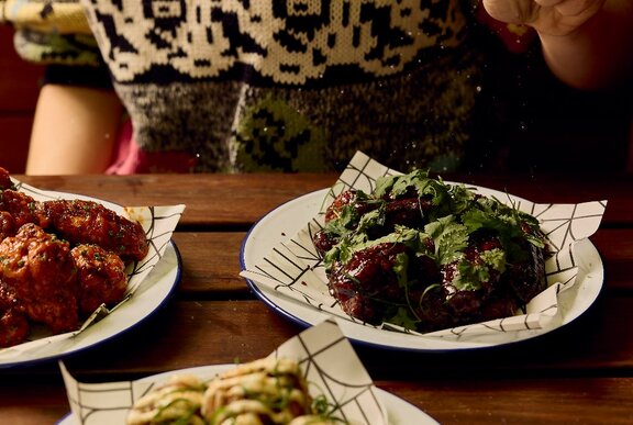 Plates of chicken wings with different marinades, a person in the background.