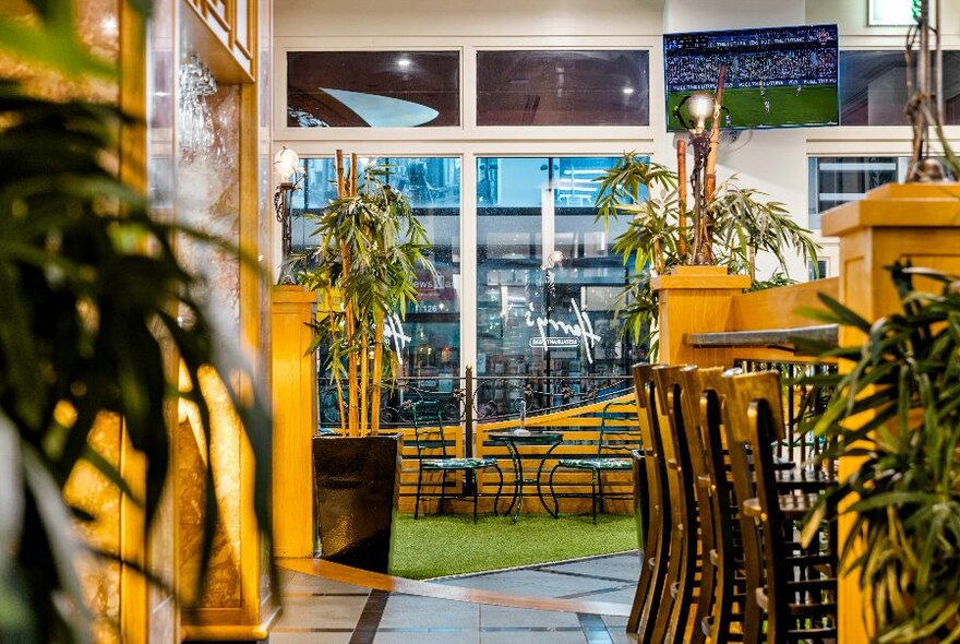 Looking through to a dining space featuring potted bamboo and yellow timber features.