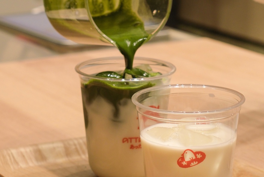 Matcha being poured from jug into takeaway cup.