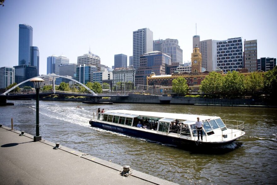 Sightseeing boat on the Yarra River with city buildings in the background.