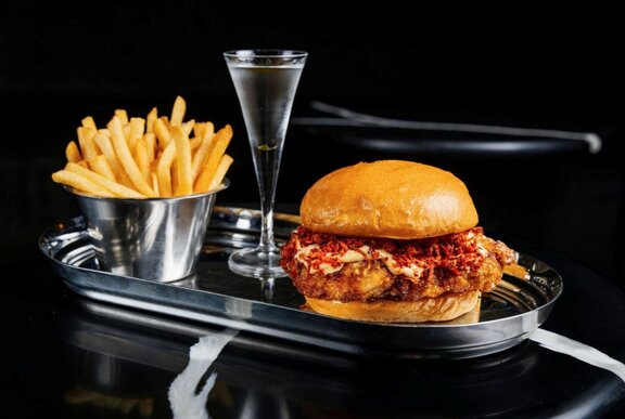 A burger, fries and mini martini served on a silver platter.