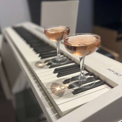 Two cocktails on top of a keyboard piano.