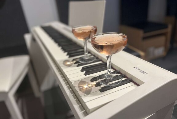 Two cocktails on top of a keyboard piano.