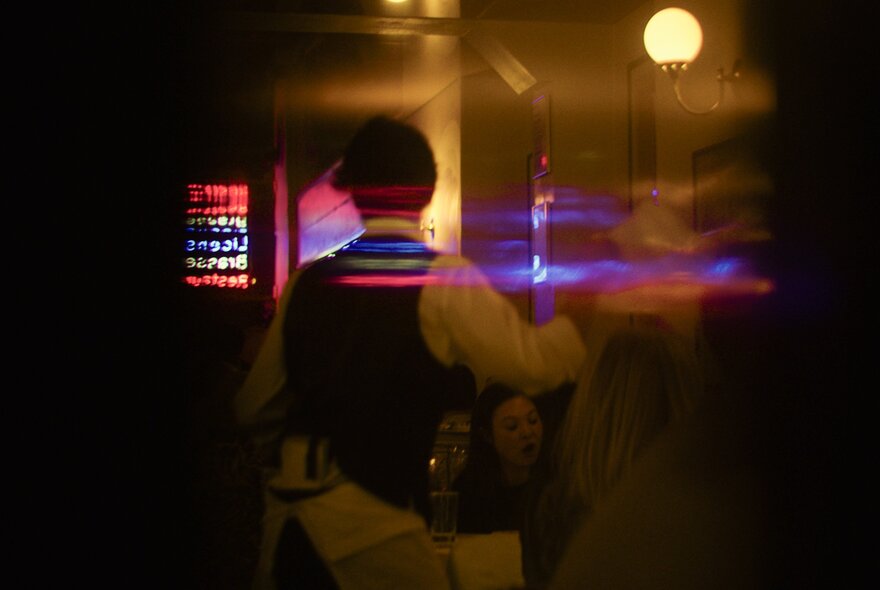 A waiter in a restaurant, blurred in motion.