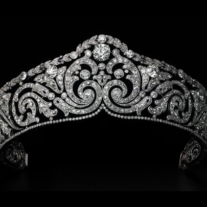 An exquisite Cartier diamond tiara, suspended against a black background. 