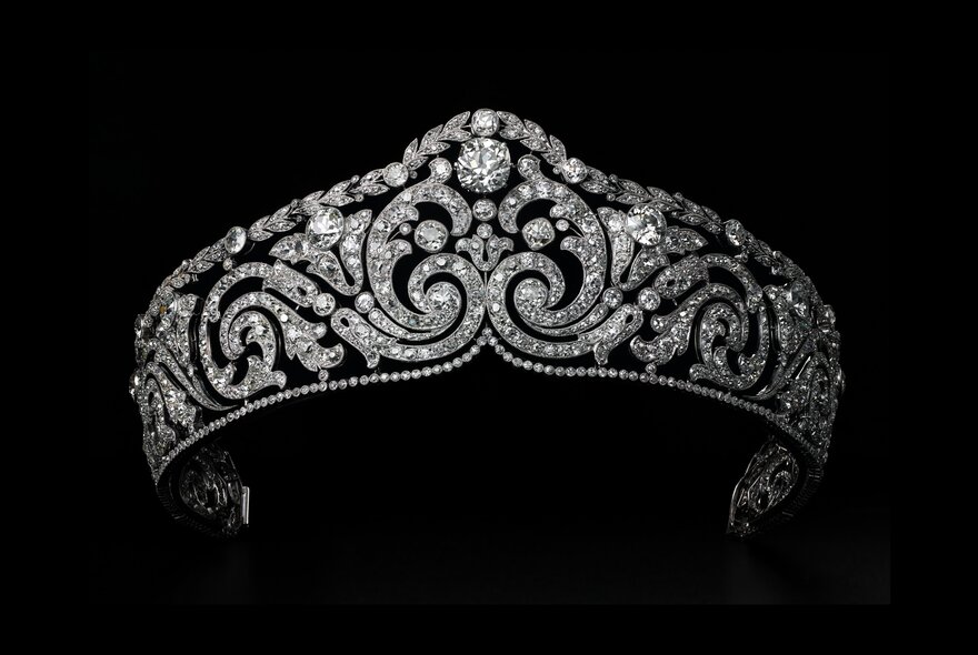 An exquisite Cartier diamond tiara, suspended against a black background. 