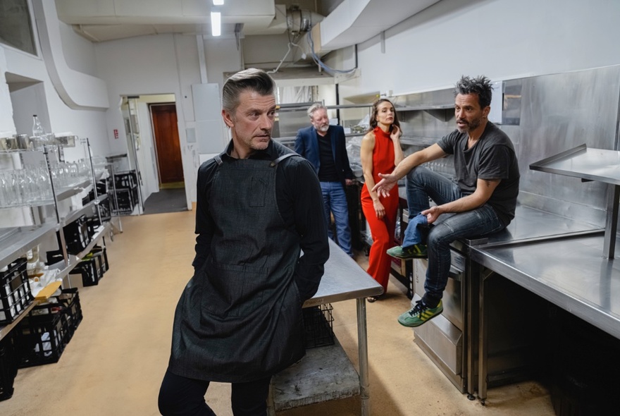 Four actors in a clean commercial kitchen, performing. 