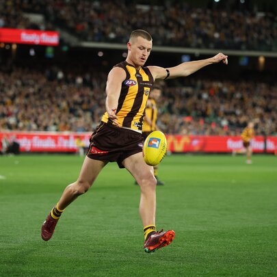 Hawthorn AFL football player about to kick a yellow ball during a match.