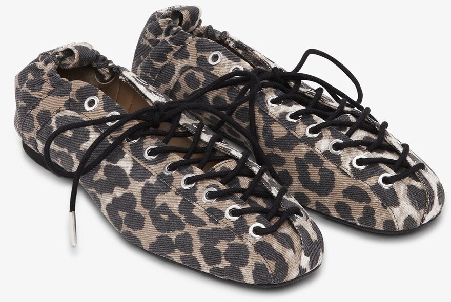A pair of leopard print ballet flats with black shoelaces.
