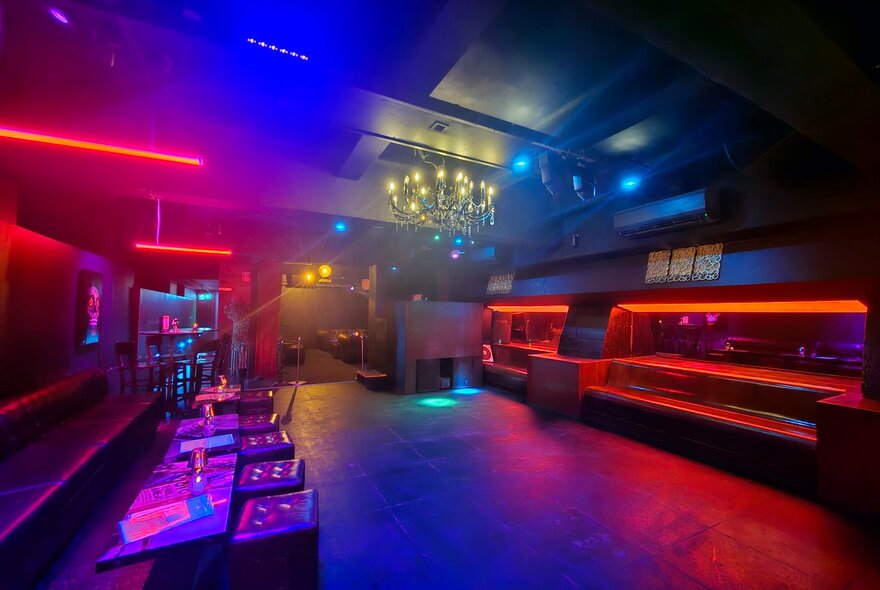 Blurred, dimly lit bar interior with purple lights and seating.