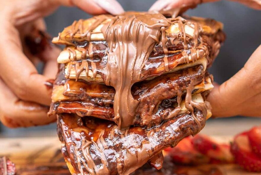 woman holding pastry covered in Nutella and strawberry 