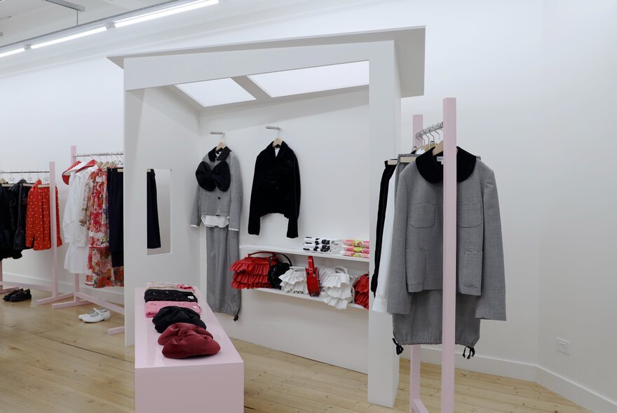A high-end clothing boutique with sparsely displayed clothing on minimalist shelving.