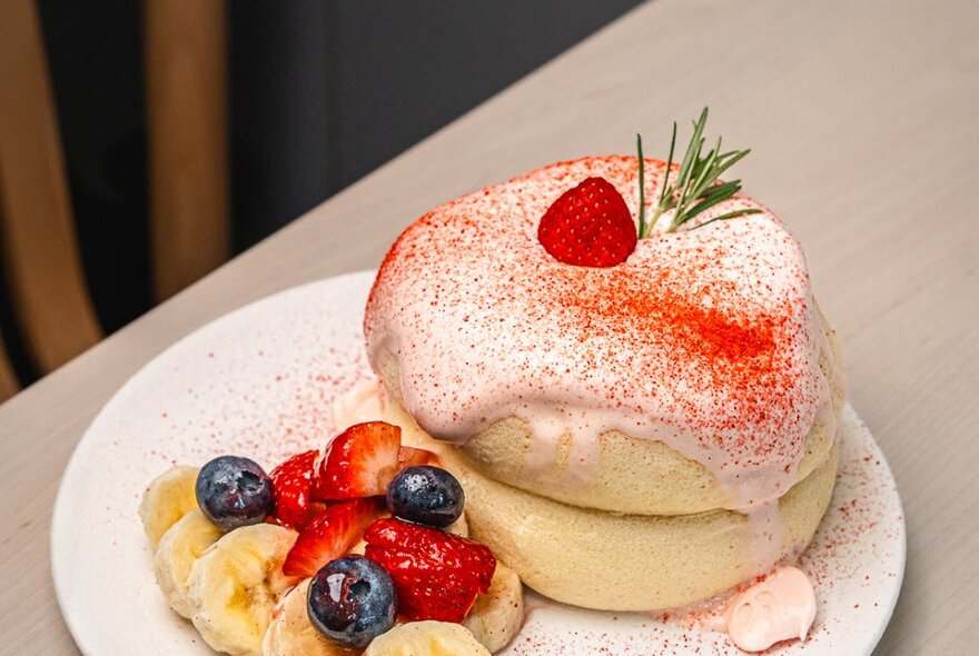 Soufflé pancakes on a plate with cream and mixed berries.