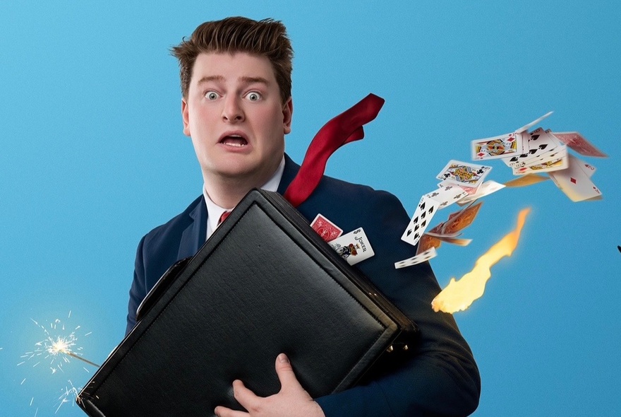 Magician Liam ‘LJ’ Jumpertz looking surprised as a gust of wind blows playing cards and scarves from his briefcase.