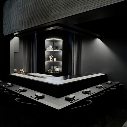 A sophisticated black dining space with low lighting centred around a chef station. 