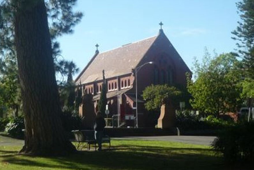 Small Victorian-era church in park setting with trees.