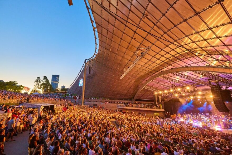 Large crowd of people watching a concert at the Sidney Myer Music Bowl. 