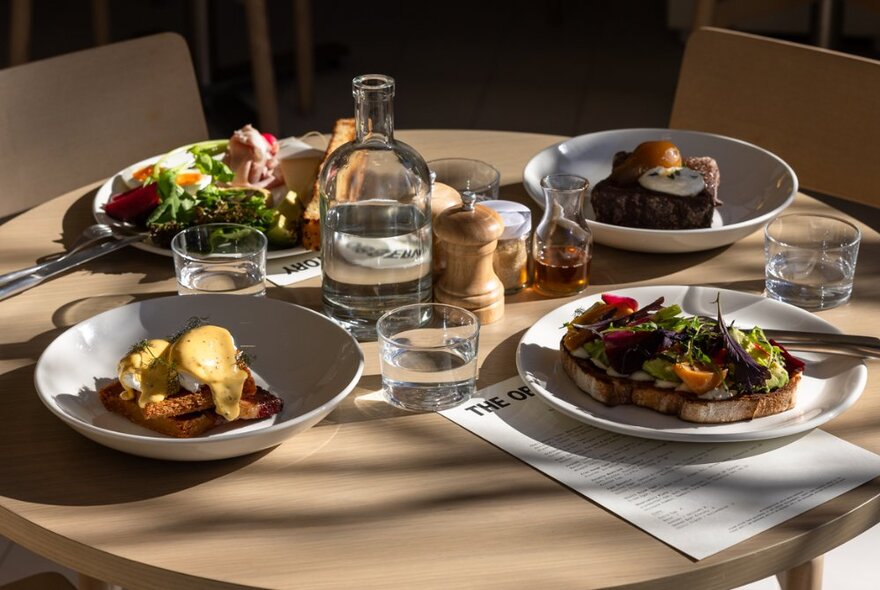 A table at The Observatory, set with four plates of brunch food, glasses of water and cutlery.