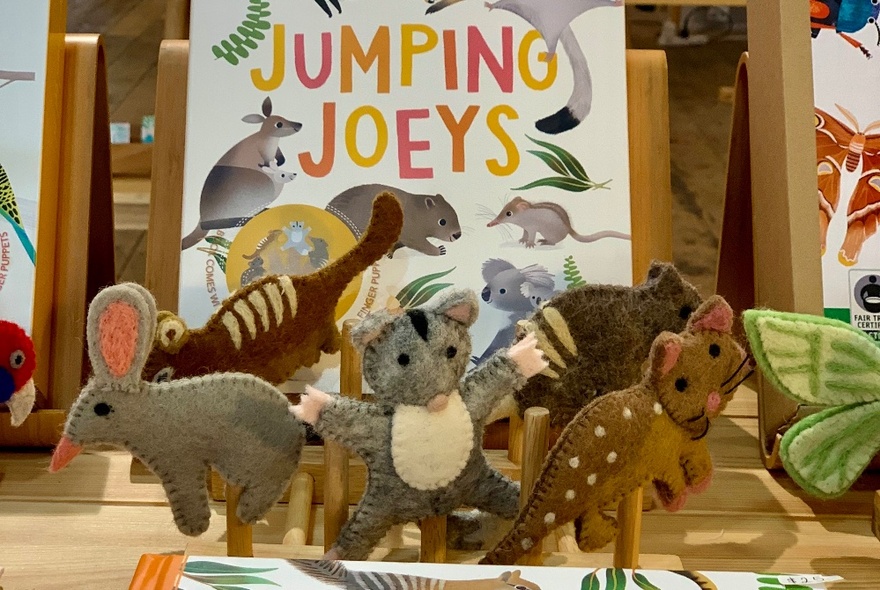 A display of small felted animal toys arranged in front of a book that has the words JUMPING JOEYS printed on the cover.