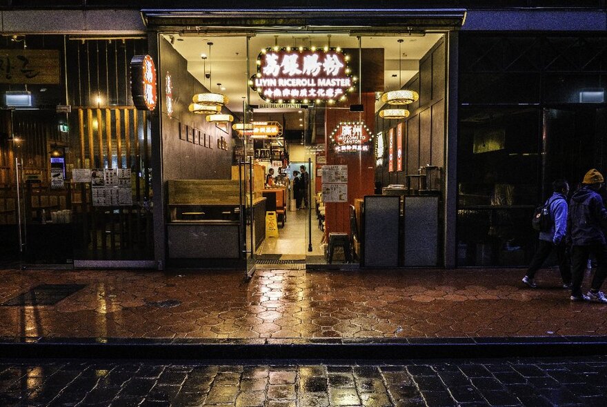 Exterior of Liyin Rice Roll Master restaurant on a wet night.