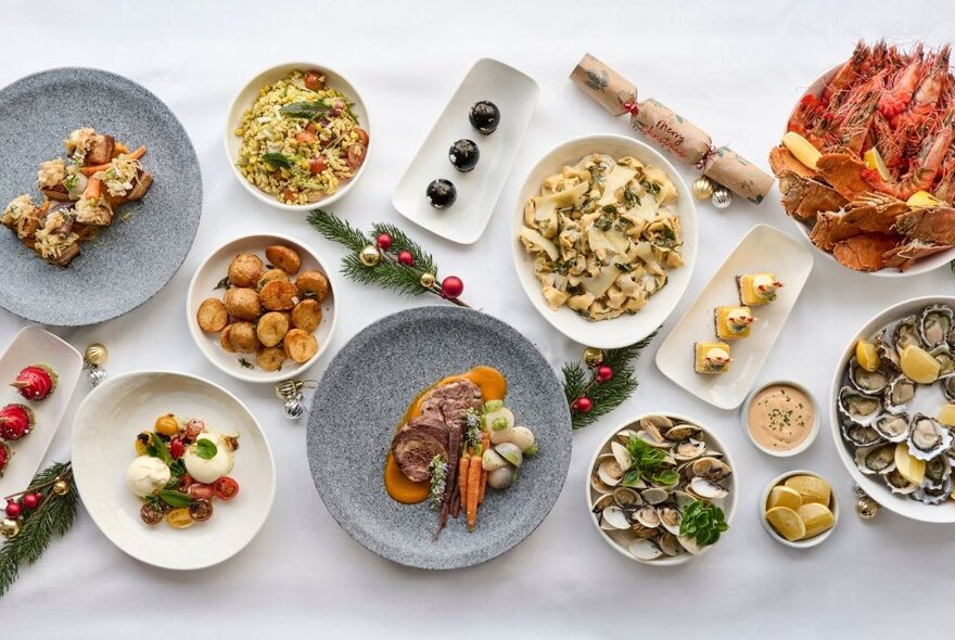 An enticing array of delicious Christmas-themed dishes, displayed on white and earthenware platters on a white surface, seen from above.